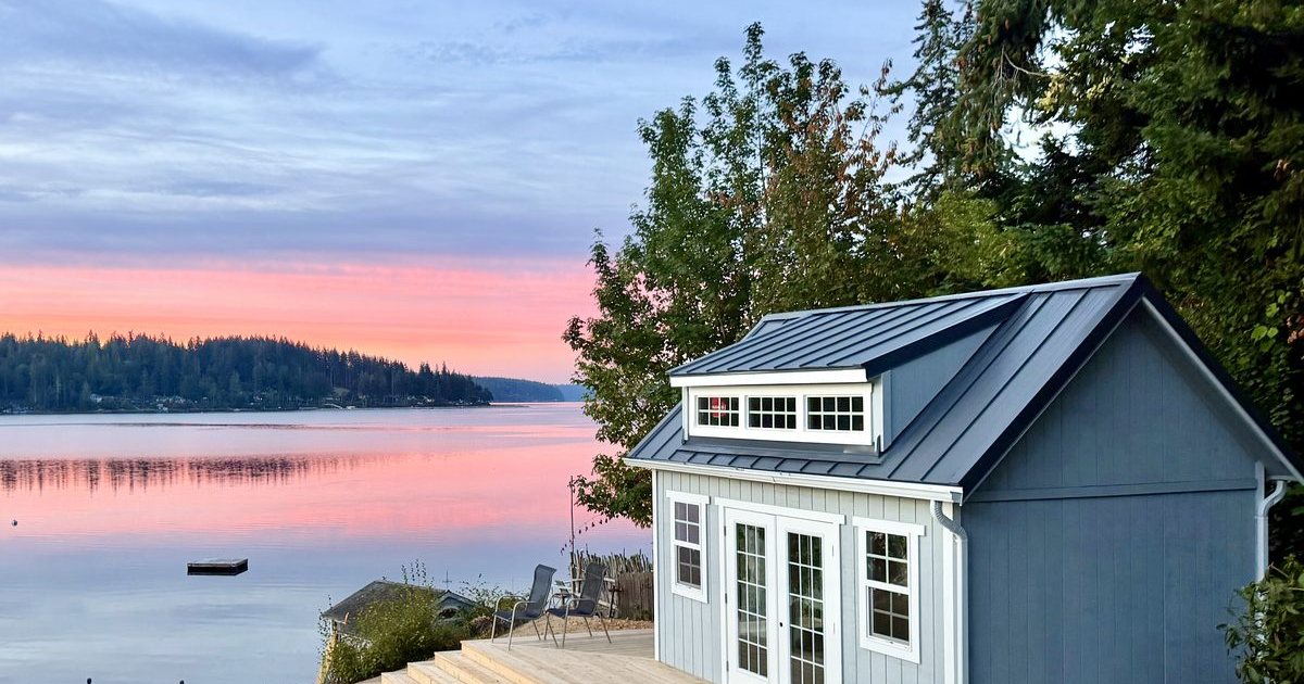 Detached accessory building with french doors and a metal roof beside a Puget Sound inlet at sunset, a KOI Build Co project