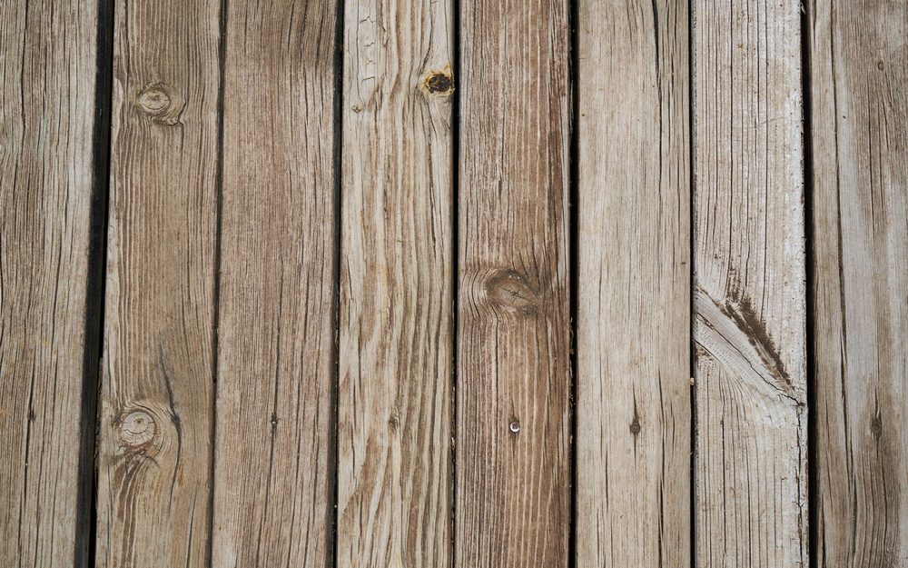 Weathered gray wood deck boards with knots and cracks
