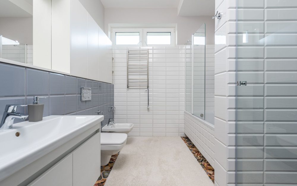 Bright white bathroom with a tiled walk-in shower, a vanity with a sink and a toilet