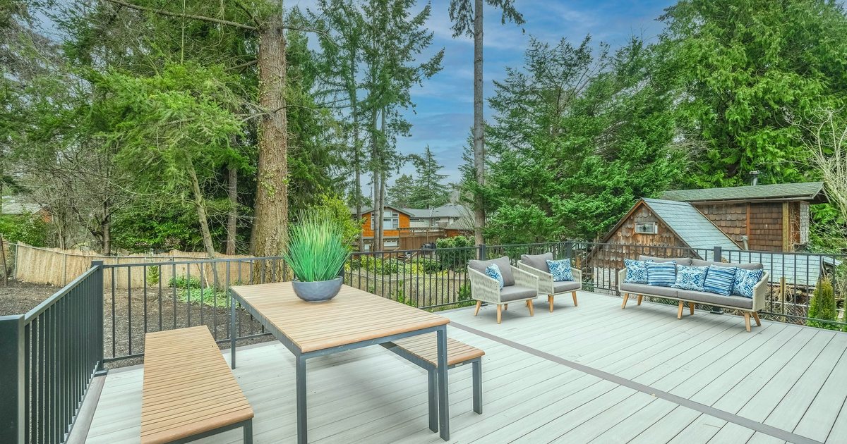 Composite deck with a dining table, benches and outdoor seating, backed by Douglas firs and a cedar-shingled shed