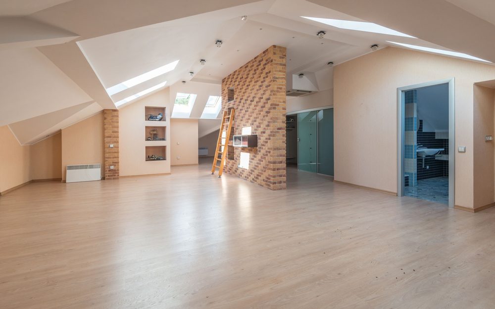 Bright open room with skylights, a light wood floor and a brick feature wall