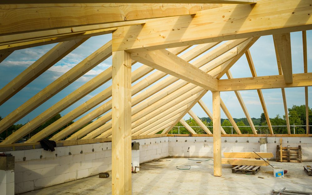 New timber roof framing going up over an upper floor, with open sky between the rafters