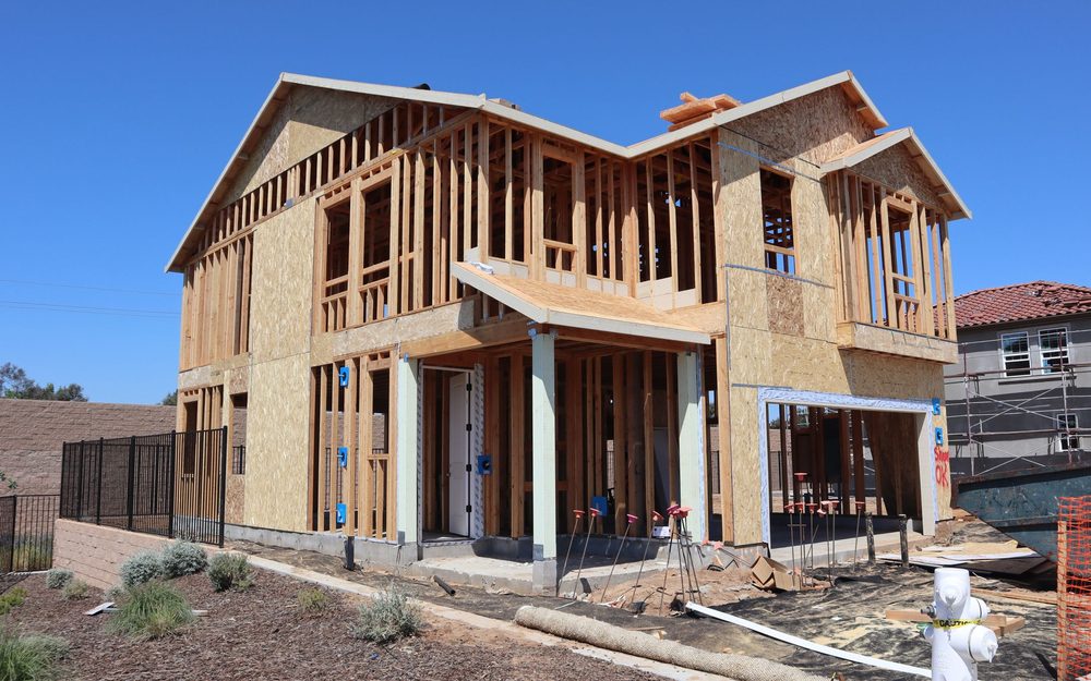 Wood-framed building with sheathing on its walls and roof, under construction against a blue sky