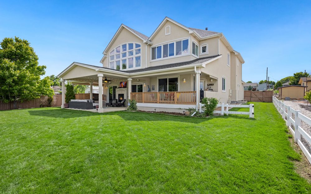 Two-story house with the main roof carried out over a covered back patio with outdoor seating and a fireplace
