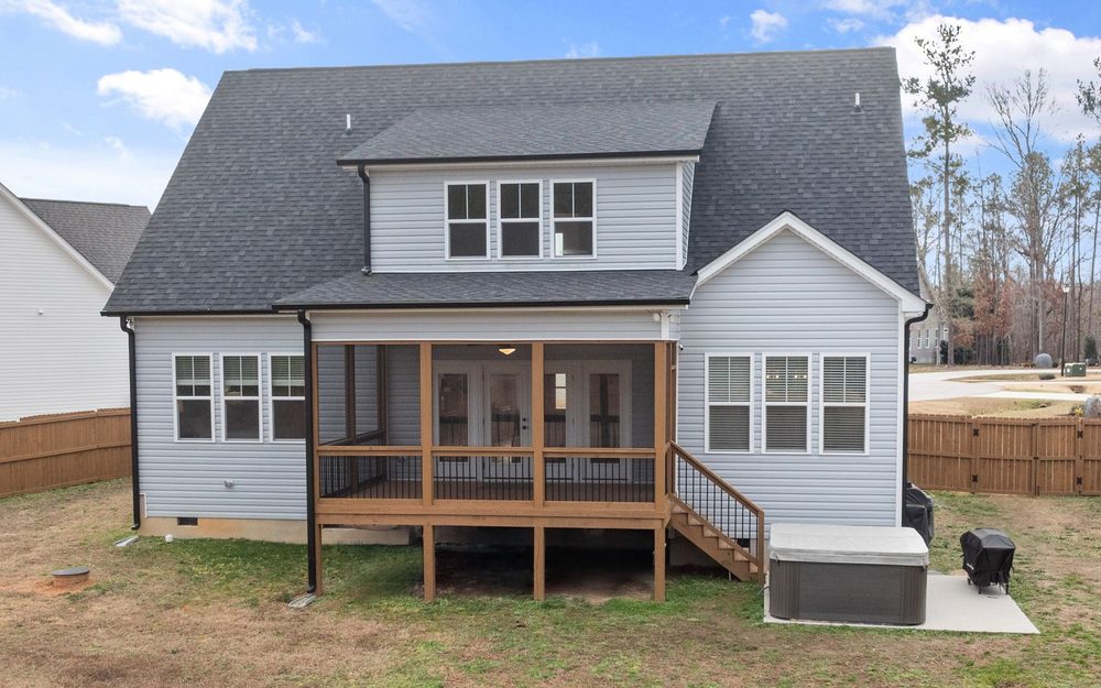 Back of a two-story house with a single-slope shed roof over a back porch, sitting below the upstairs windows
