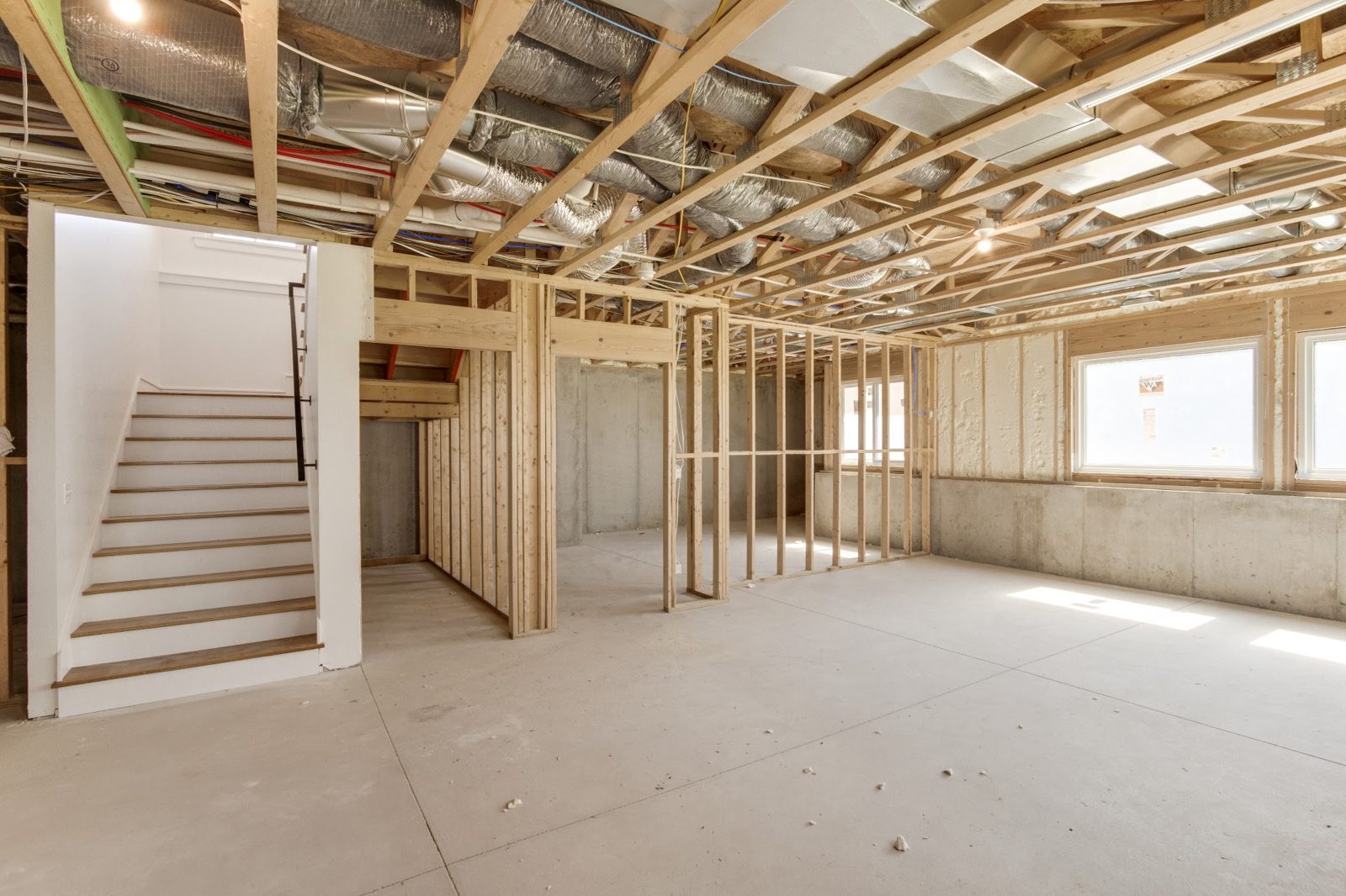 New stud walls framed inside an unfinished space with ductwork and wiring run overhead, a KOI Build Co project