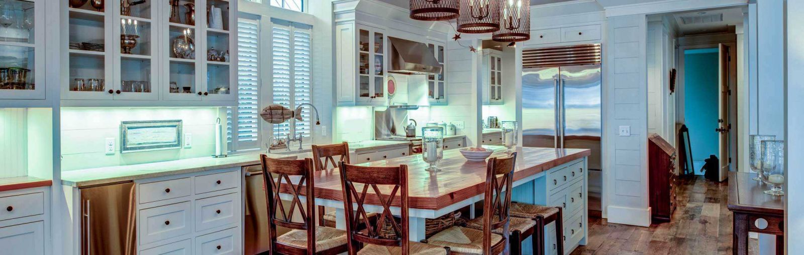 A kitchen featuring a wooden table surrounded by four chairs, with cabinets and appliances in the background.