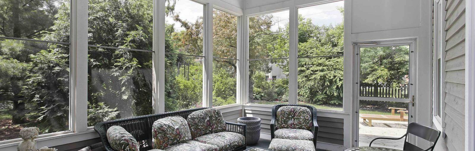 A sunroom featuring a cozy couch and several chairs, inviting natural light and a relaxing atmosphere.