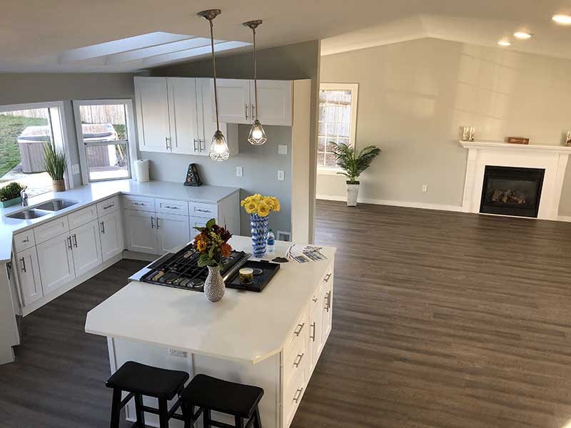 A modern kitchen featuring a white island and warm wooden floors, creating a bright and inviting atmosphere.