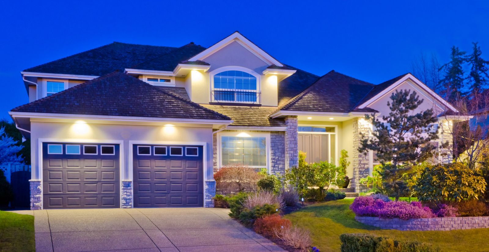 A well-lit home with a driveway and garage, showcasing its charm under the night sky.