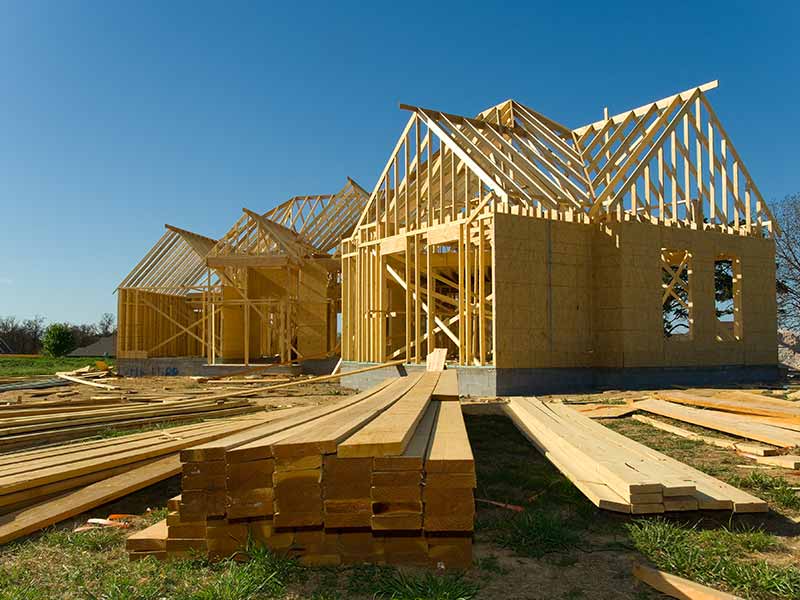 A house under construction featuring exposed wooden framing and scaffolding in a residential area.